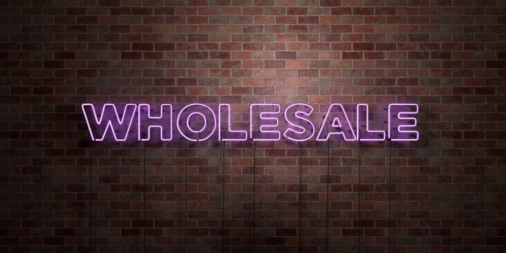 An image of the word wholesale written in neon on a brick wall.